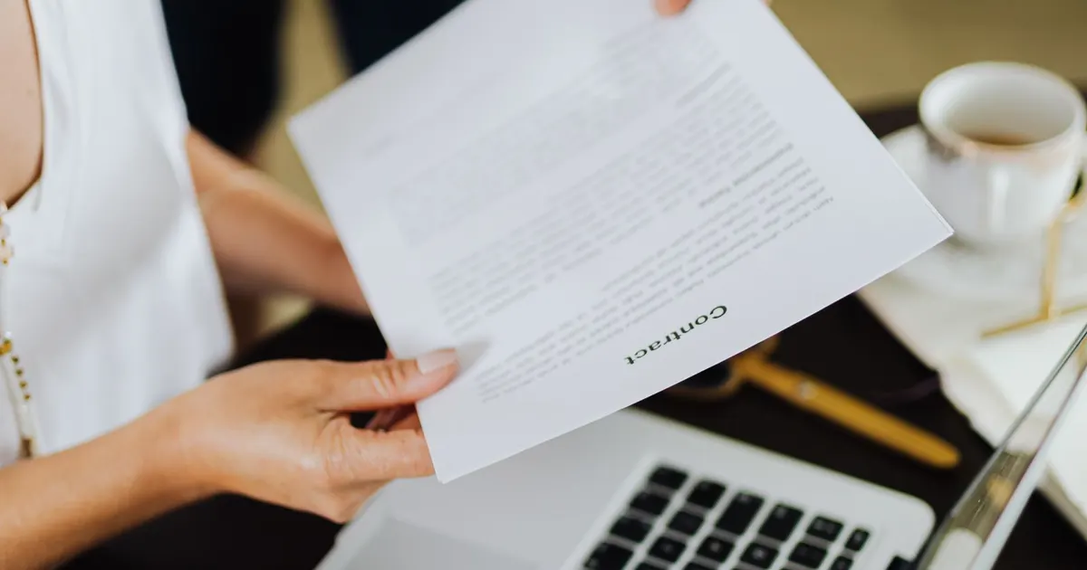 Deux personnes échangeant un document au-dessus d’un ordinateur