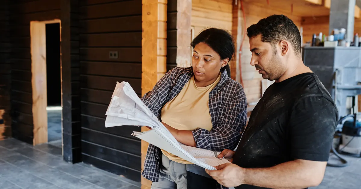Deux professionnels relisant des plans dans un bâtiment en travaux