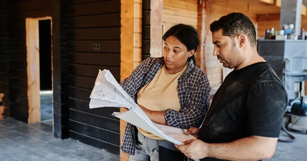 Deux professionnels relisant des plans dans un bâtiment en travaux