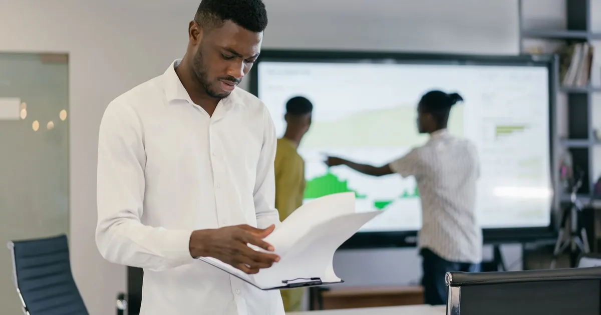 Professionnel lisant un document au bureau pendant une réunion de travail.