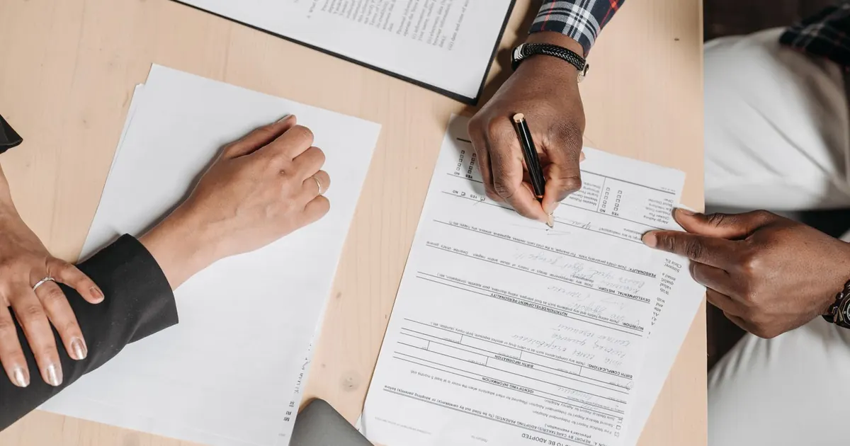 Deux personnes relisent et signent des documents sur une table de travail.