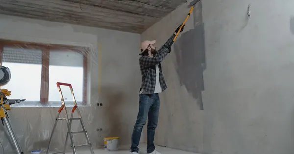 Peintre appliquant la peinture près d’une fenêtre protégée