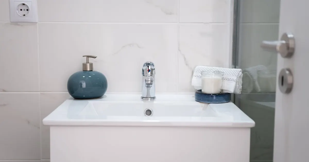 Lavabo blanc et robinetterie chromée dans une salle d’eau