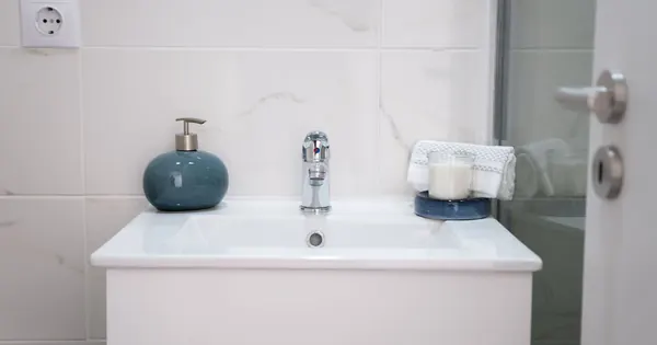 Lavabo blanc et robinetterie chromée dans une salle d’eau