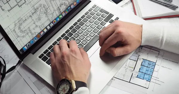 Consultation de plans sur une table avec un ordinateur