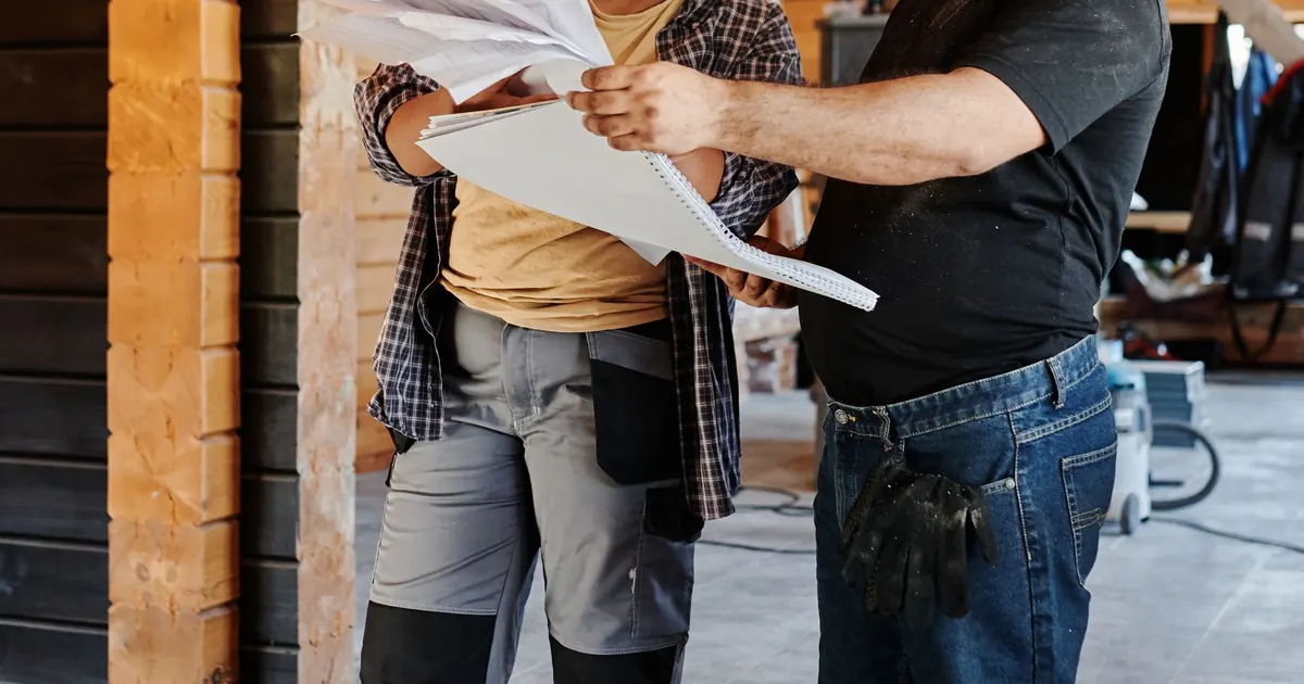 Deux professionnels examinent des plans dans une structure en bois