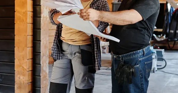 Deux professionnels examinent des plans dans une structure en bois