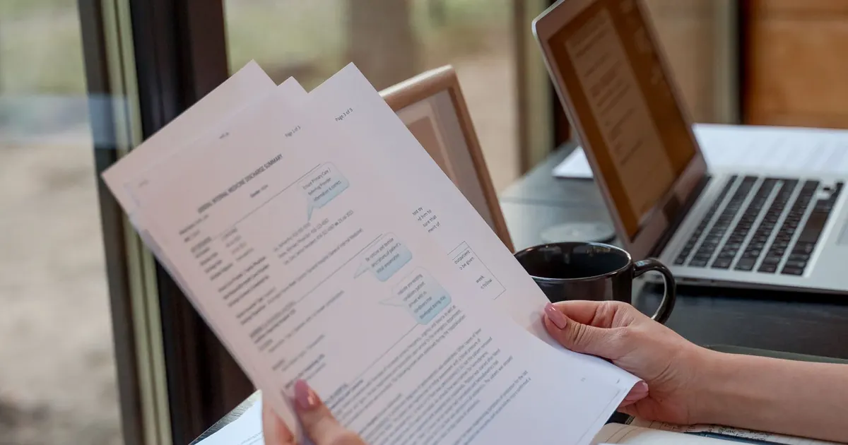 Personne consultant un document près de son ordinateur