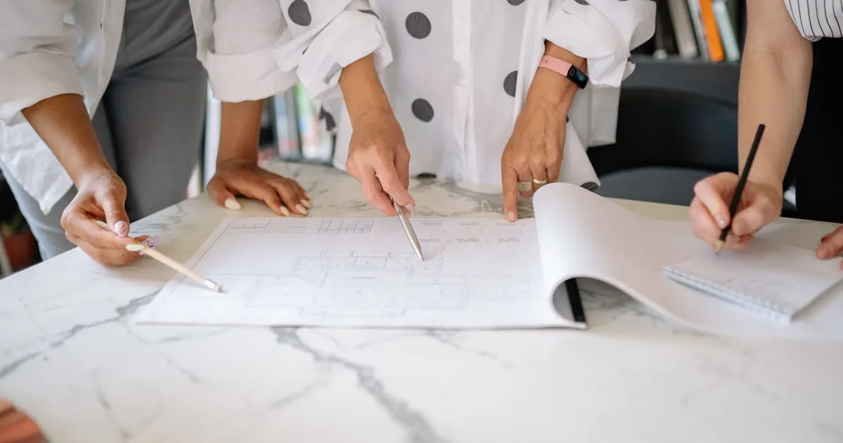 Travail collectif sur un plan de bâtiment, avec annotations au crayon
