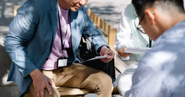 Trois professionnels relisent des documents lors d’un échange de travail.