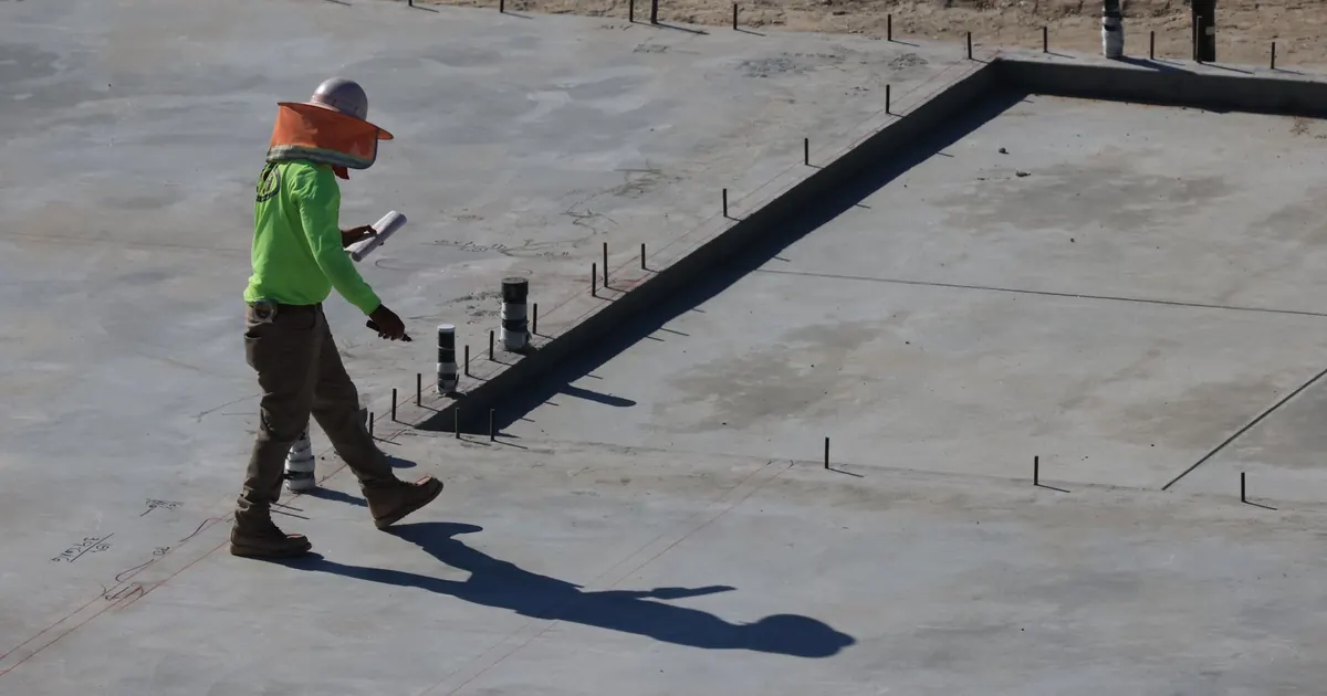 Personne équipée se déplaçant sur une dalle de chantier
