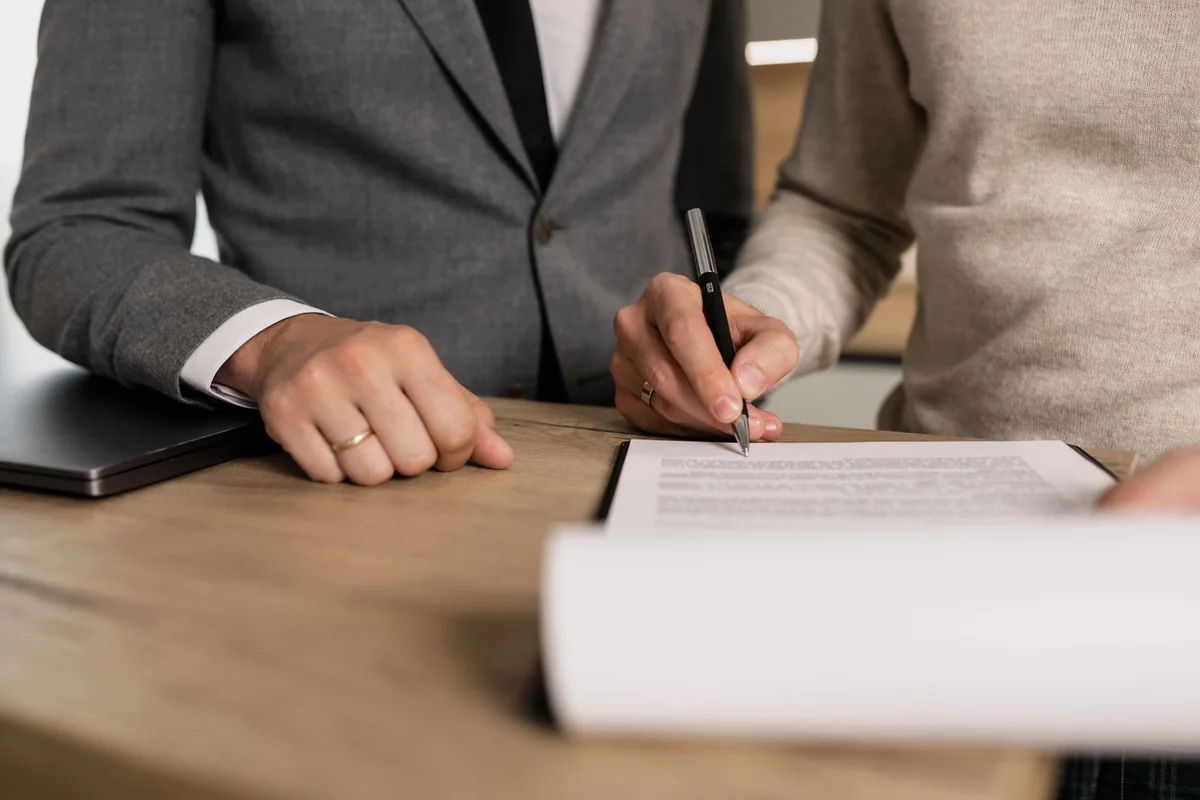 Deux personnes examinent un document, stylo en main, à une table.